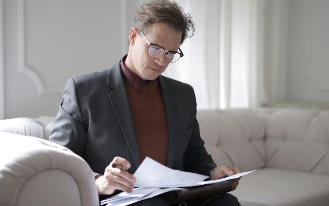 Man sitting on couch looking at paperwork living trust