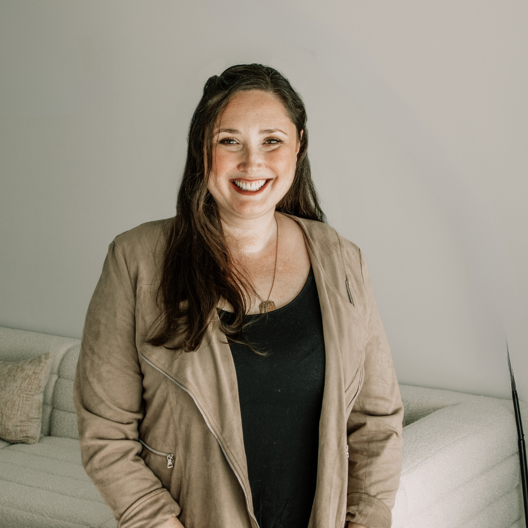 Smiling woman stands in front of cream background