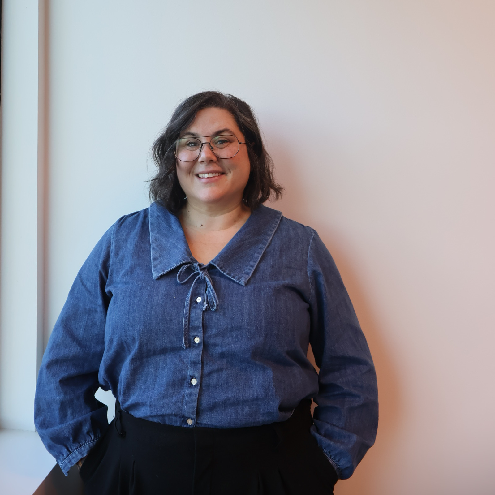 Staff member wearing collared blue shirt smiles into the camera.